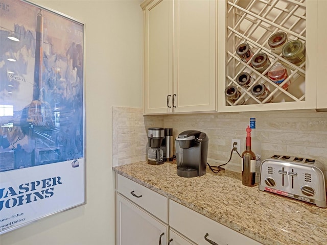 interior space with a toaster, white cabinetry, light stone counters, and backsplash