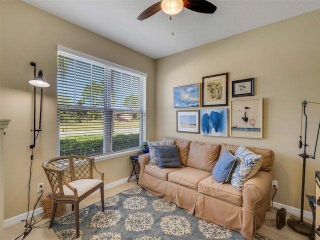 living area with a ceiling fan and baseboards