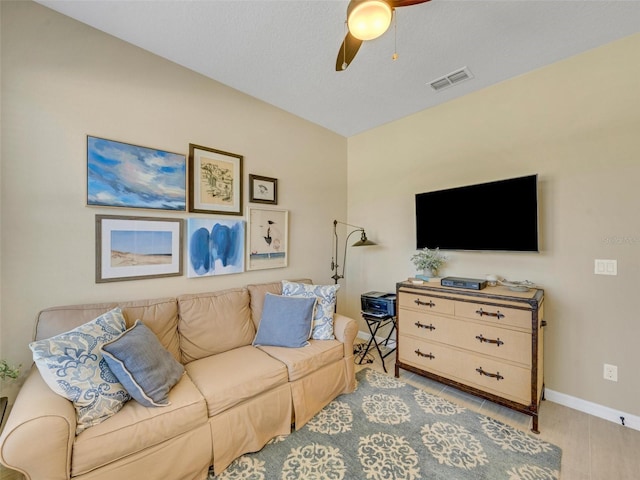 living room with light wood finished floors, baseboards, visible vents, and a ceiling fan