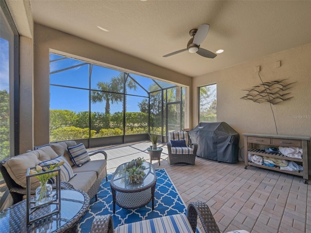 view of patio featuring ceiling fan, glass enclosure, grilling area, and an outdoor living space