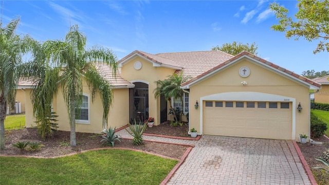 mediterranean / spanish-style house with a tile roof, decorative driveway, a garage, and stucco siding