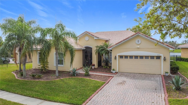 mediterranean / spanish home with an attached garage, stucco siding, a front lawn, a tiled roof, and decorative driveway