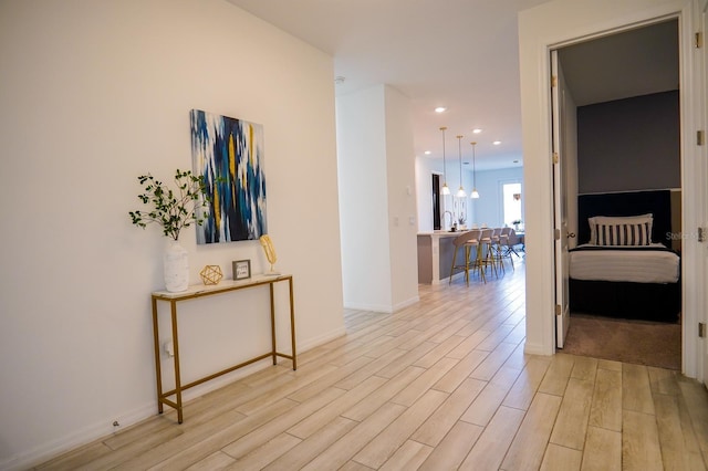 corridor featuring recessed lighting, light wood-style flooring, and baseboards