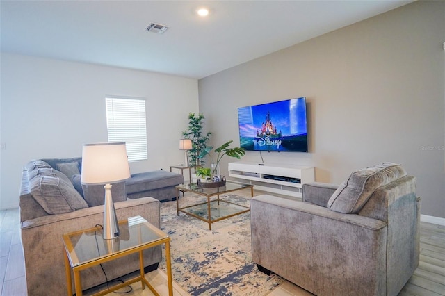 living area with wood finished floors, visible vents, and baseboards