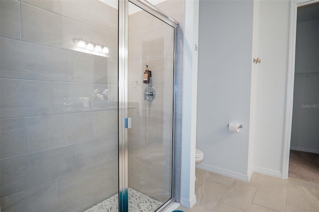 bathroom featuring tile patterned flooring, toilet, a shower stall, and baseboards