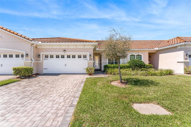 mediterranean / spanish home with stucco siding, an attached garage, decorative driveway, and a front yard