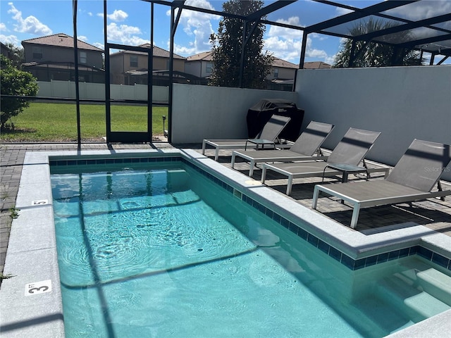 view of pool featuring glass enclosure, a patio area, a fenced in pool, and a yard