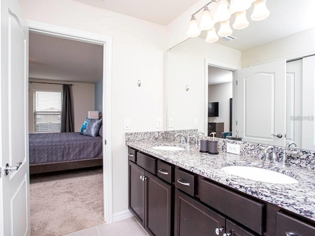 full bath featuring double vanity, an inviting chandelier, ensuite bathroom, and a sink