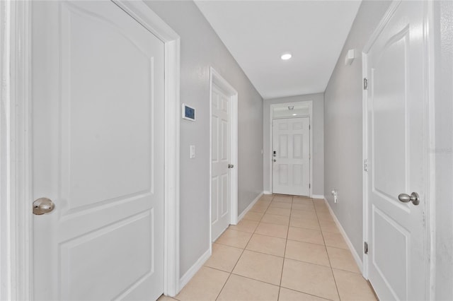 corridor with light tile patterned floors and baseboards