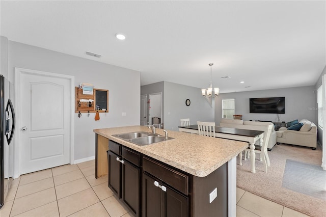 kitchen featuring light countertops, visible vents, a sink, dark brown cabinetry, and a chandelier