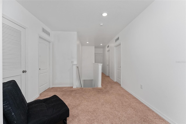 sitting room featuring visible vents, baseboards, carpet, an upstairs landing, and recessed lighting