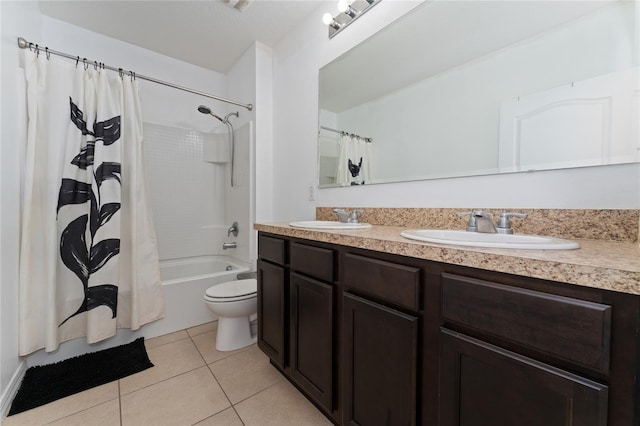 bathroom with double vanity, toilet, a sink, and tile patterned floors