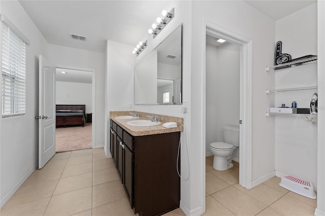 ensuite bathroom with toilet, tile patterned flooring, visible vents, and a sink