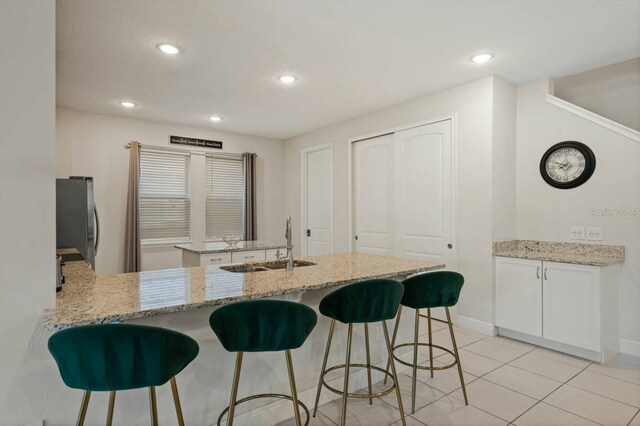 kitchen with freestanding refrigerator, a sink, a peninsula, and a breakfast bar area