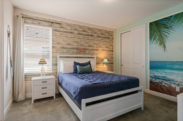 bedroom featuring baseboards, an accent wall, and light colored carpet