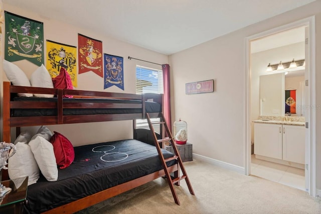 bedroom featuring baseboards, connected bathroom, and light colored carpet