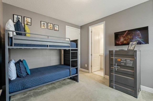 carpeted bedroom featuring ensuite bath, a textured ceiling, and baseboards