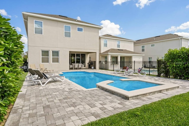 back of property with stucco siding, fence, a fenced in pool, and a patio