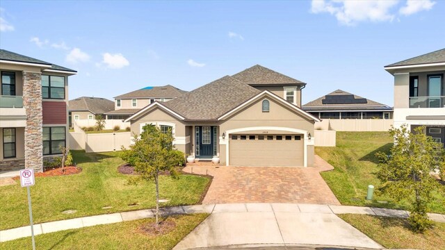 view of front of house with stucco siding, a front lawn, decorative driveway, fence, and a garage