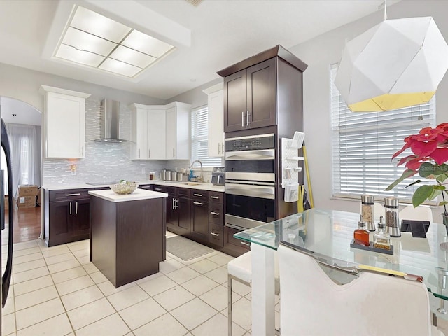 1718 Golfview Dr, Kissimmee, FL 34746 - kitchen featuring double oven, dark brown cabinetry, wall chimney range hood, backsplash, and stovetop