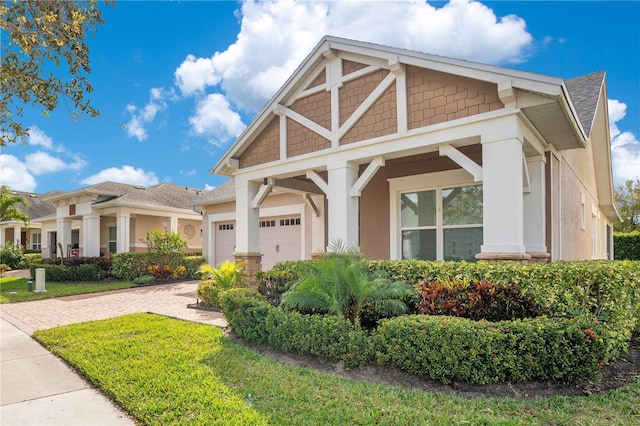 view of front of home with decorative driveway, an attached garage, and stucco siding