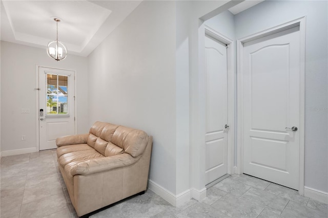 entrance foyer featuring a notable chandelier, a tray ceiling, and baseboards