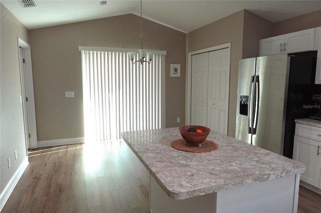 kitchen with stainless steel fridge, white cabinets, wood finished floors, and vaulted ceiling