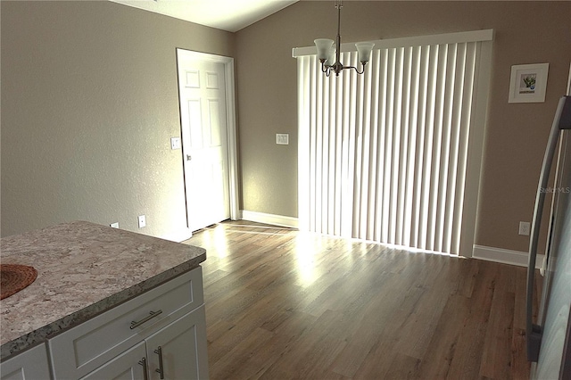 dining room with a notable chandelier, baseboards, lofted ceiling, and wood finished floors