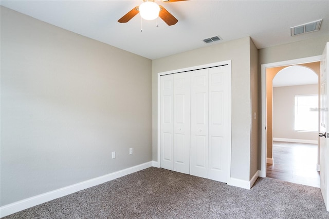 unfurnished bedroom with arched walkways, visible vents, baseboards, and carpet floors