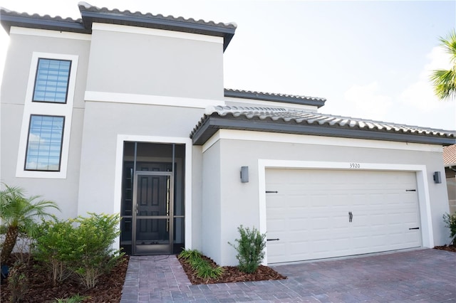 mediterranean / spanish home with decorative driveway, a tile roof, and stucco siding