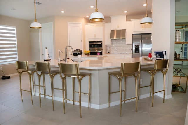 kitchen featuring visible vents, decorative backsplash, appliances with stainless steel finishes, a sink, and under cabinet range hood