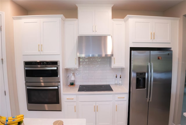 kitchen featuring exhaust hood, white cabinetry, light countertops, appliances with stainless steel finishes, and backsplash