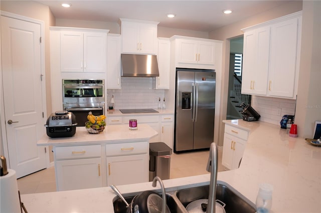 kitchen featuring appliances with stainless steel finishes, extractor fan, decorative backsplash, and white cabinets