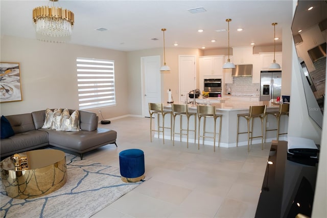 living area with baseboards, a notable chandelier, visible vents, and recessed lighting