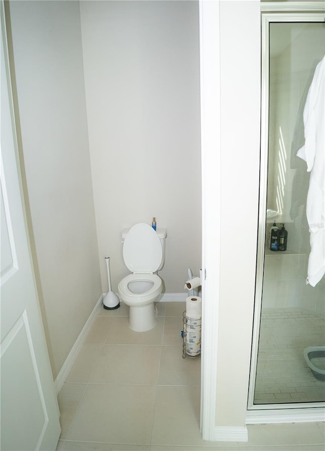 bathroom with a stall shower, tile patterned flooring, baseboards, and toilet