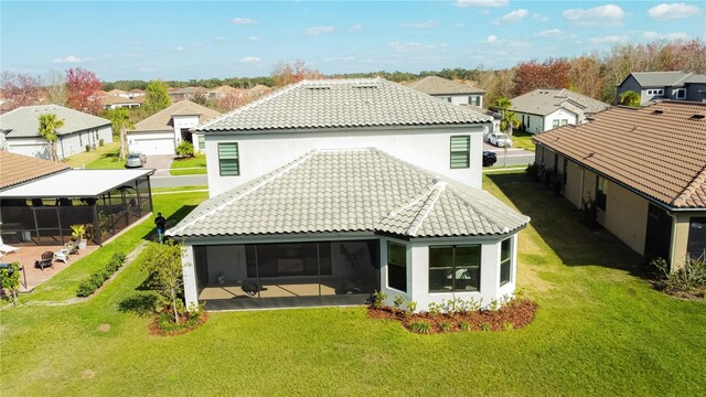 back of house with a lawn, a residential view, a tile roof, and a sunroom