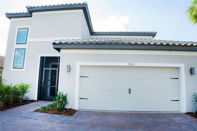 exterior space featuring decorative driveway, a tile roof, and stucco siding