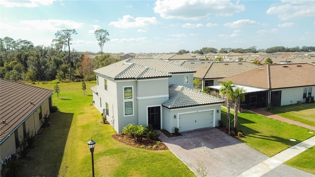 view of front of property featuring decorative driveway, a tile roof, stucco siding, a garage, and a front lawn