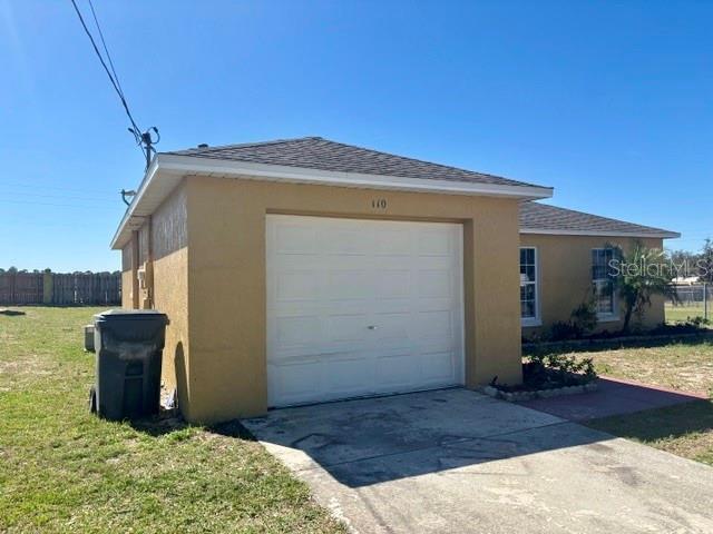 garage with fence and concrete driveway