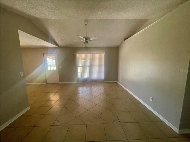 tiled empty room featuring vaulted ceiling, ceiling fan, a textured ceiling, and baseboards