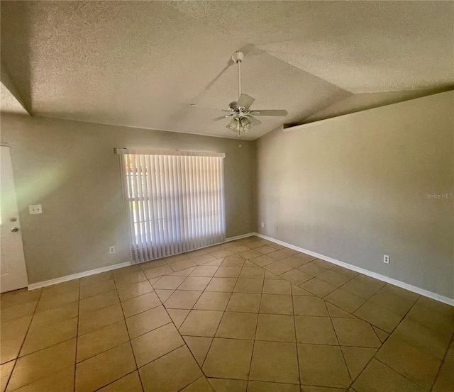 tiled spare room featuring lofted ceiling, a textured ceiling, baseboards, and a ceiling fan