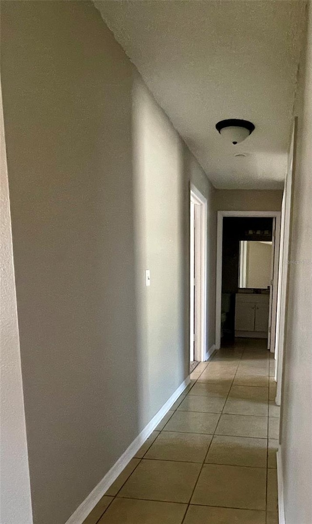 hallway with light tile patterned flooring and baseboards