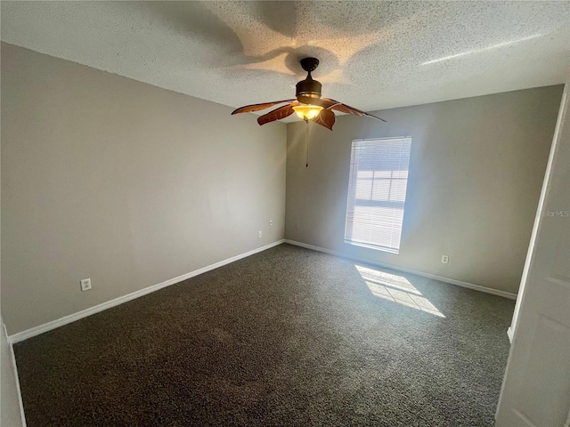 spare room with a ceiling fan, baseboards, dark carpet, and a textured ceiling