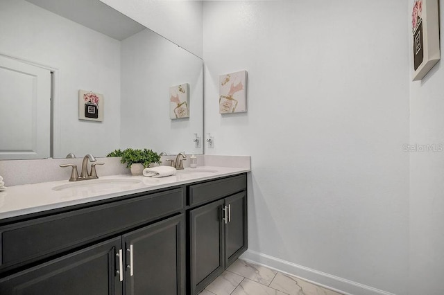 bathroom featuring a sink, baseboards, marble finish floor, and double vanity