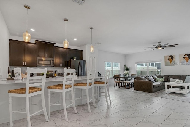 kitchen featuring a kitchen bar, marble finish floor, decorative light fixtures, stainless steel appliances, and dark brown cabinets