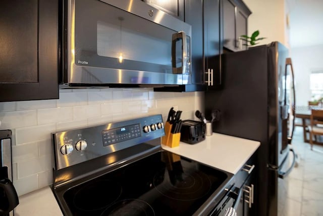 kitchen featuring decorative backsplash, stainless steel microwave, light countertops, and range with electric stovetop