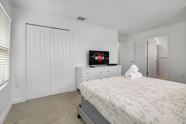 bedroom featuring a closet, visible vents, light colored carpet, and multiple windows