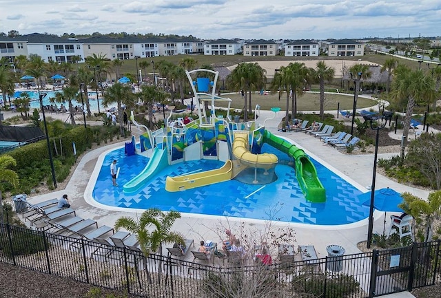 view of pool featuring playground community, fence, and a residential view