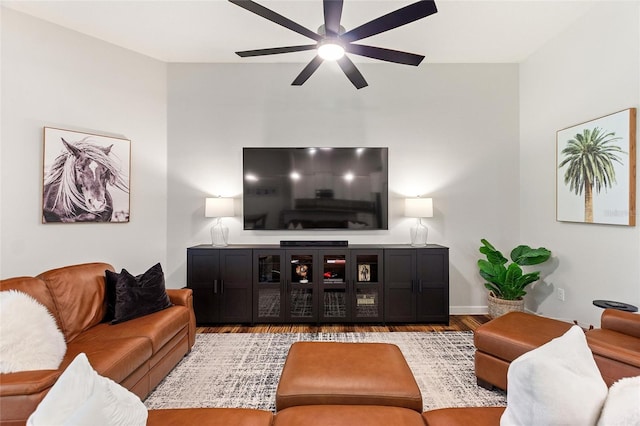 living area with a ceiling fan, baseboards, and wood finished floors