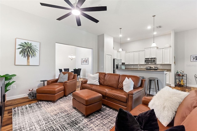 living area with recessed lighting, ceiling fan with notable chandelier, wood finished floors, visible vents, and baseboards